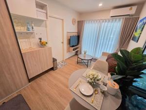 a living room with a couch and a table with flowers at Phyll Condo Room in Wichit in Ban Rangeng