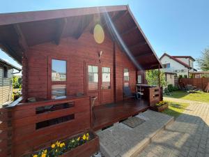 a large wooden cabin with a deck with a desk at Domki Letniskowe ARTEMI in Rowy