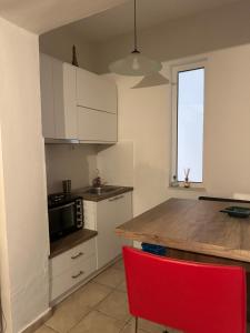 a kitchen with white cabinets and a red chair at The salty studio in Rethymno