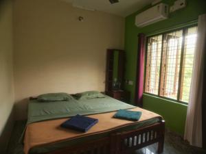 a bedroom with a bed with green walls and a window at PONMUDI DALE. HOMESTAY in Kallar-Bridge