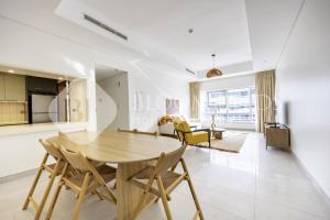 a dining room and living room with a wooden table and chairs at Bloomfields 2BR in Lamar Raha Beach in Abu Dhabi