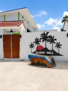 a surfboard sitting in front of a white building at Samui Hills Resort in Taling Ngam Beach