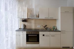 a kitchen with white cabinets and a stove top oven at Zirbitzblick in Mönchegg +23 photos