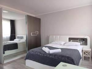 a white bedroom with two beds and a mirror at Napolá apartman in Balatonalmádi