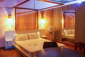 a bedroom with a bed and a table and a mirror at Marionel Hôtel in Ampilahoa