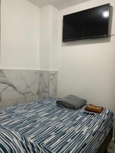 a bedroom with a bed with a flat screen tv on the wall at Hostal Belletini in Manta