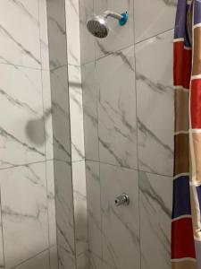 a shower with marble tiles and a shower head at Hostal Belletini in Manta