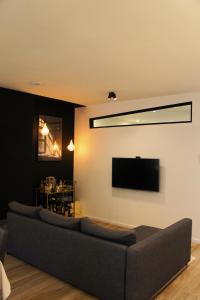 a living room with a couch and a flat screen tv at Hébergement atypique in Esch-sur-Sûre