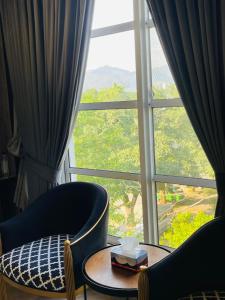 a room with a large window with a table and chairs at Three Trees Hotel Islamabad in Islamabad