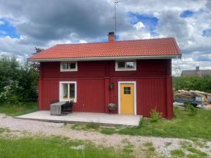 a red house with a yellow door in a field at Lissmogården in Leksand