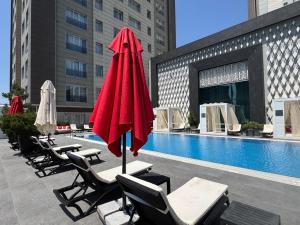 a pool with lounge chairs and a red umbrella at Bishkek Park Apartments in Bishkek