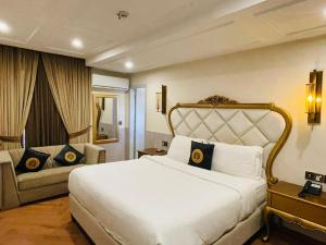 a bedroom with a large white bed and a couch at Three Trees Hotel Islamabad in Islamabad