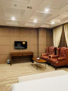 a living room with two chairs and a flat screen tv at Three Trees Hotel Islamabad in Islamabad