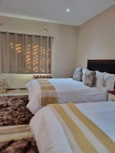 a hotel room with two beds and a window at Wild Haven Lodge in Victoria Falls