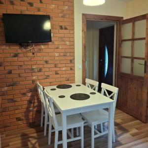 a white table with chairs and a tv on a brick wall at Domki i apartamenty nad jeziorem solińskim z basenem I widokiem na góry in Wołkowyja