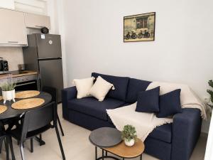 a living room with a blue couch and a kitchen at Aelia Blu 1 in Ofrínion +6 photos