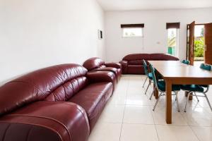 a living room with a leather couch and a table at Urbanview Hotel RDN Oasis Cisarua by RedDoorz in Brujul +17 photos