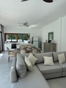 a living room with a gray couch and a kitchen at Villa Palm Sip Sam in Ko Phangan