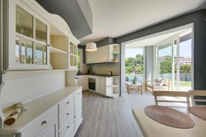 a kitchen with white cabinets and a large window at Chillout House with heated pool 29 C Sea & Mountain view in Santa Susanna