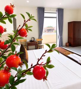 a bedroom with a bed and a tree with red fruit at Hotel QUỐC TUẤN in Ban Ay Dlă (2)