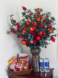a vase with a bouquet of fruit and drinks on a table at Hotel QUỐC TUẤN in Ban Ay Dlă (2)