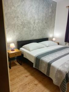 a bedroom with a bed and two tables with lamps at Tangerine Apartment in Rabac