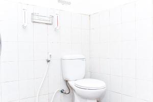 a bathroom with a toilet in a white tiled wall at RedDoorz near UGM 3 in Yogyakarta