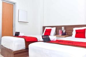 two beds in a room with red and white at RedDoorz near UGM 3 in Yogyakarta +18 photos