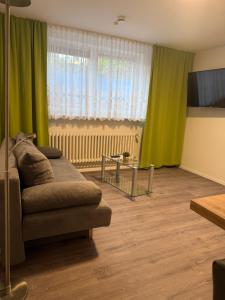 a living room with green curtains and a couch at Dünenhaus Souterrain Strandallee 3 in Timmendorfer Strand