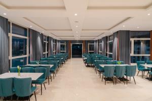 a restaurant with blue chairs and tables and windows at Nature Hotel and Suite in Da Lat