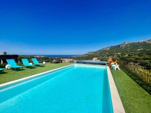 a blue swimming pool with blue chairs and a mountain at Villa Mare Monti in Lumio