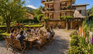 a group of people sitting around a table in front of a building at Ortensia Apartment for 4 near Lake Como and Lugano in Lanzo dʼIntelvi
