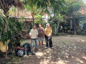 a family posing for a picture in a garden at Pondok IJo Guesthouse in Yogyakarta