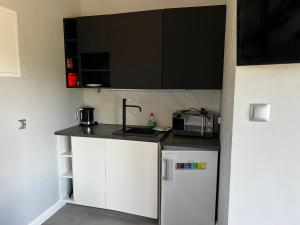 a small kitchen with white cabinets and a sink at Domek Za Wyspą 1 in Chmielów