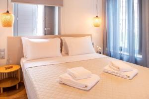 a bedroom with a white bed with towels on it at Gaia Trikeri Suites in Ayía Kiriakí