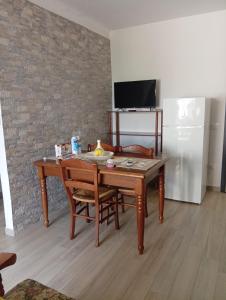 a kitchen with a wooden table with chairs and a refrigerator at Casa di nonna Caterina in Nemoli +5 photos