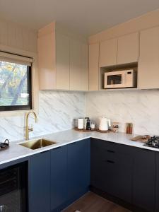 Eine Küche mit blauen Schränken, Spüle und Mikrowelle in der Unterkunft Zenith Tiny Home in Montacute