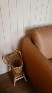 ein braunes Sofa und ein Korb neben einem Stuhl in der Unterkunft Zenith Tiny Home in Montacute