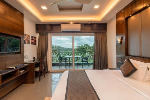 a bedroom with a bed and a balcony with a table at Hotel Altitude Coorg in Madikeri