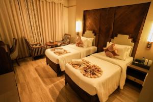 a hotel room with two beds and a table and chairs at raj Regent kurichy in Putuppalli +85 photos