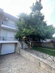 a white house with a tree and a fence at Villa VG- Calm and relax in Nea Vrasna