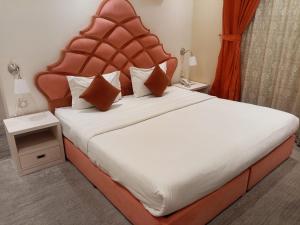 a bedroom with a large bed with a red headboard at شقق برج نوران للشقق المخدومة Nouran Tower Serviced Apartments in Al Khobar +43 photos