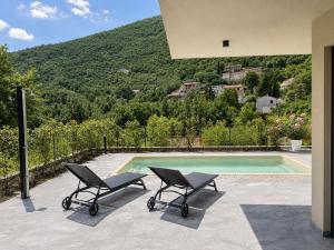 a pair of chairs sitting next to a swimming pool at Villa Perla di Draga in Mošćenička Draga