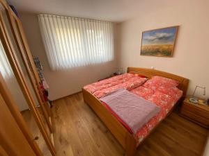 a bedroom with a bed with a red comforter and a window at Schöne 2-Zimmer-Souterrainwohnung mit Terrasse in Offenburg