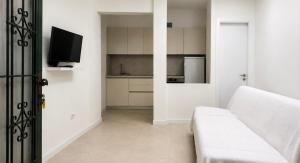 a white living room with a white couch and a tv at Studios Annie in Bijela