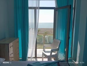 a bedroom with a chair and a window with the ocean at Hotel Marina in Shekhvetili