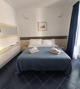 ein Schlafzimmer mit einem blauen Bett, auf dem zwei Handtücher liegen in der Unterkunft Tuareg Hotel in Campomarino