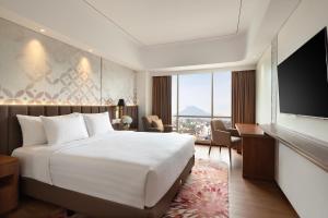 a hotel room with a bed and a flat screen tv at Atria Hotel Malang in Malang