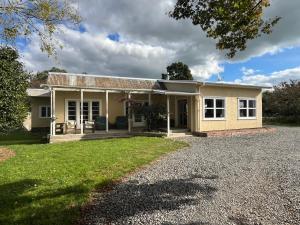 a house with a gravel driveway in front of it at Destination Cliff Top - Cottage and Homestead in Ohingaiti