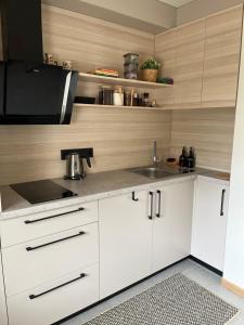 a kitchen with white cabinets and a sink at Lapu ielas apartment in Ogre +8 photos